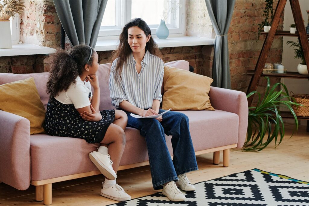 A support worker sitting with a young person in the living room of an Invigor home
