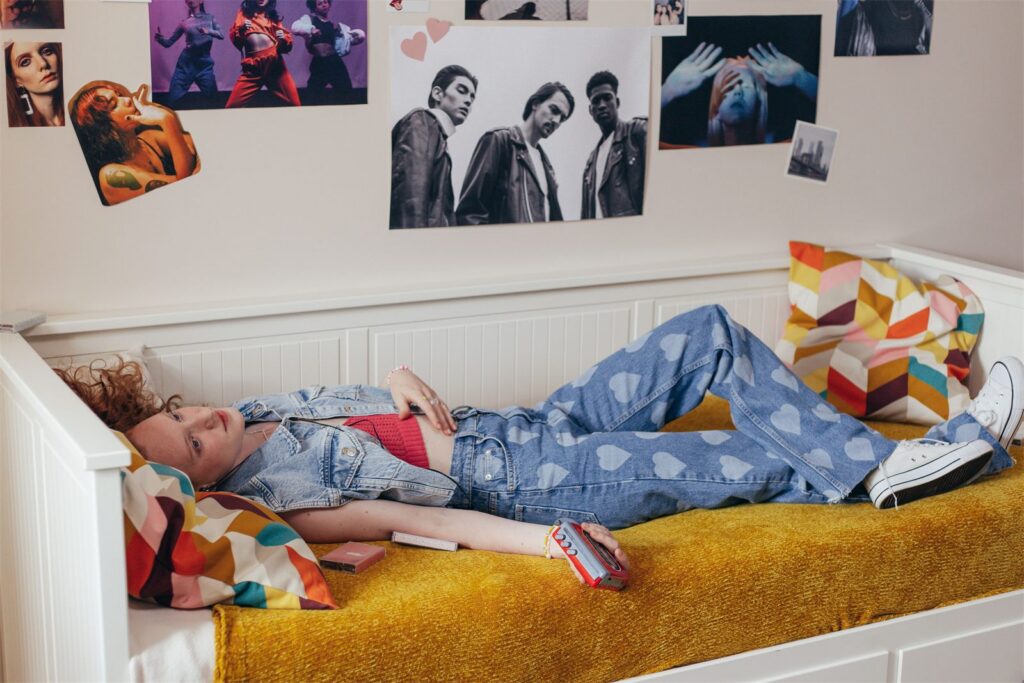 A young person relaxing in their own bedroom, personalised with posters