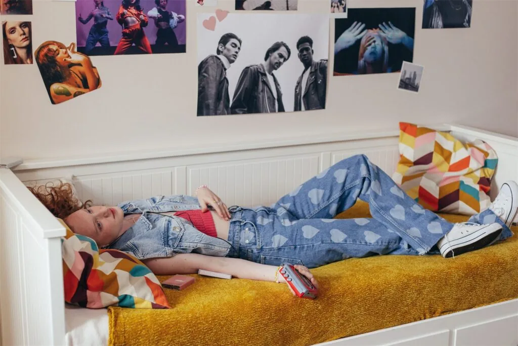 A young person relaxing in their own bedroom, personalised with posters