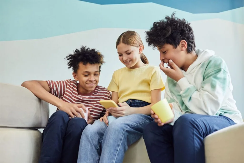 Three young people laughing together on a sofa